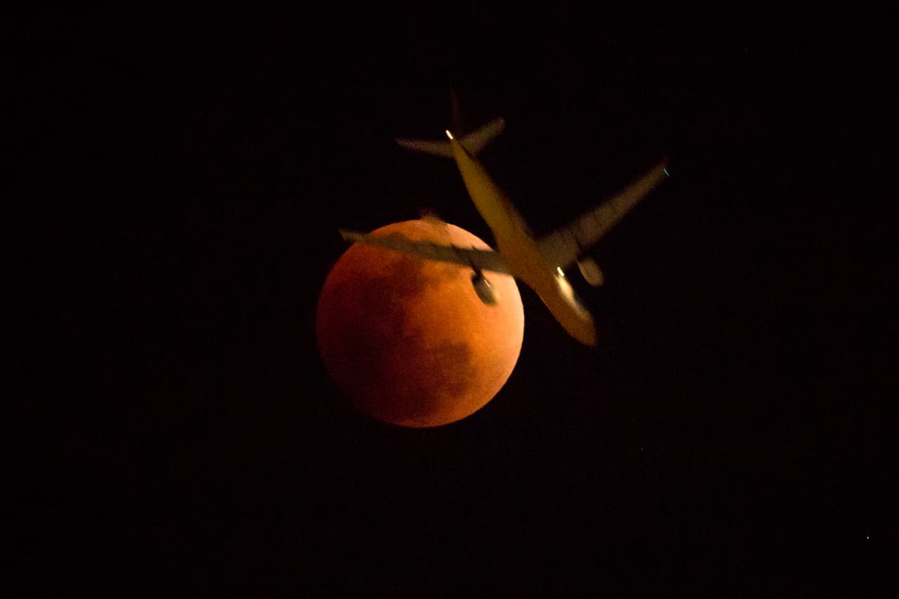 Un avión vuela frente a la luna eclipsada en Hong Kong.