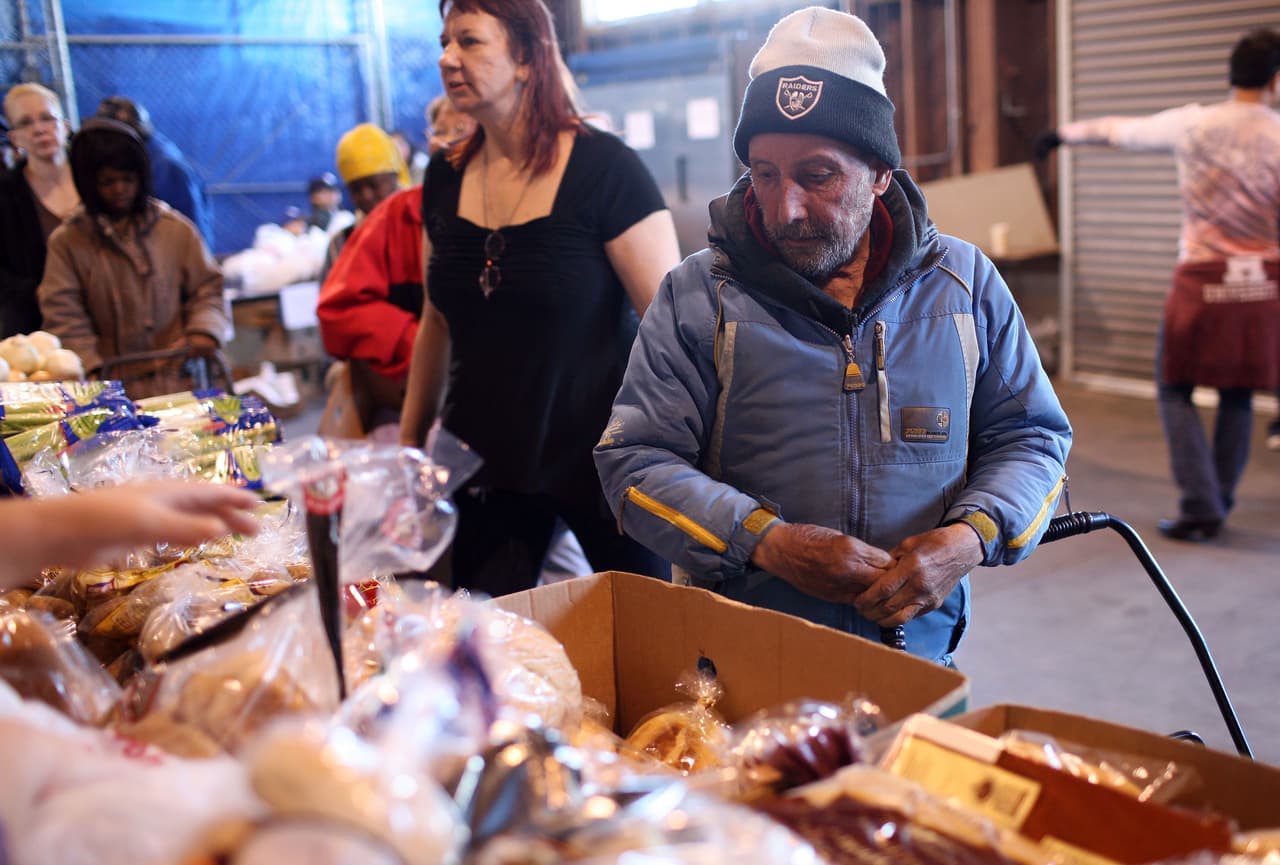 <b>50 millones de estadounidenses podrían necesitar <a href="https://www.feedingamerica.org/hunger-in-america/facts?s_src=Y20YP1B1Z&s_keyword=feeding%20america&s_subsrc=c&_ga=2.206837587.1133148200.1606320160-391345894.1606320160&_gac=1.12765125.1606320160.CjwKCAiAnvj9BRA4EiwAuUMDf8Yed06SIsy0ApOupSGyJkR_iTEPyROFzZeB_ZyqGzPx9g2jWCzMIBoCpjMQAvD_BwE">ayuda alimentaria para el final de 2020</a>, según Feeding America.</b> Esta organización, que maneja uno de los bancos de alimentos más grandes del país, estima que este total incluye a unos 17 millones de niños. En la fotografía, un hombre en la fila para recibir los insumos para la cena de Acción de Gracias en Alameda, California, el 24 de noviembre.