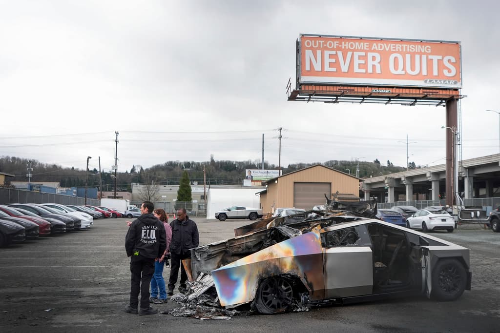 Investigadores de la ATF y un miembro del Departamento de Bomberos de Seattle inspeccionan Cybertrucks de Tesla quemados en un lote de Tesla en Seattle, el lunes 10 de marzo de 2025. (AP Foto/Lindsey Wasson)