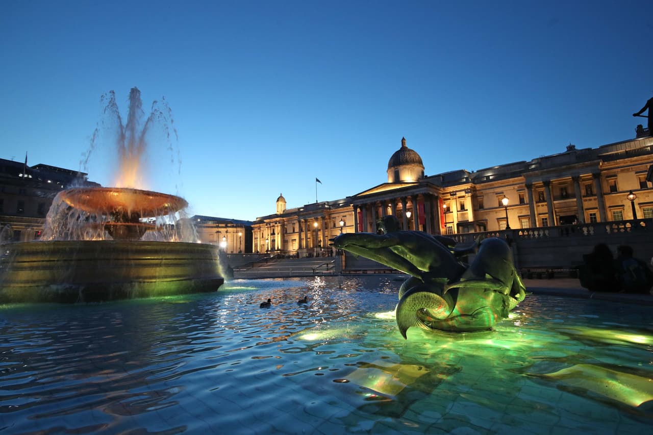 La plaza trafalgar de Londres iluminada por el ‘Día Nacional de Reflexión’, al atardecer del 23 de marzo. La pandemia también golpeó duramente a la economía británica, que sufrió su recesión más profunda en más de 300 años. Johnson insiste en que el plan de su gobierno para levantar las restricciones se guiará por "datos, no fechas", pero que la vida podría ser mucho más normal el próximo verano.
