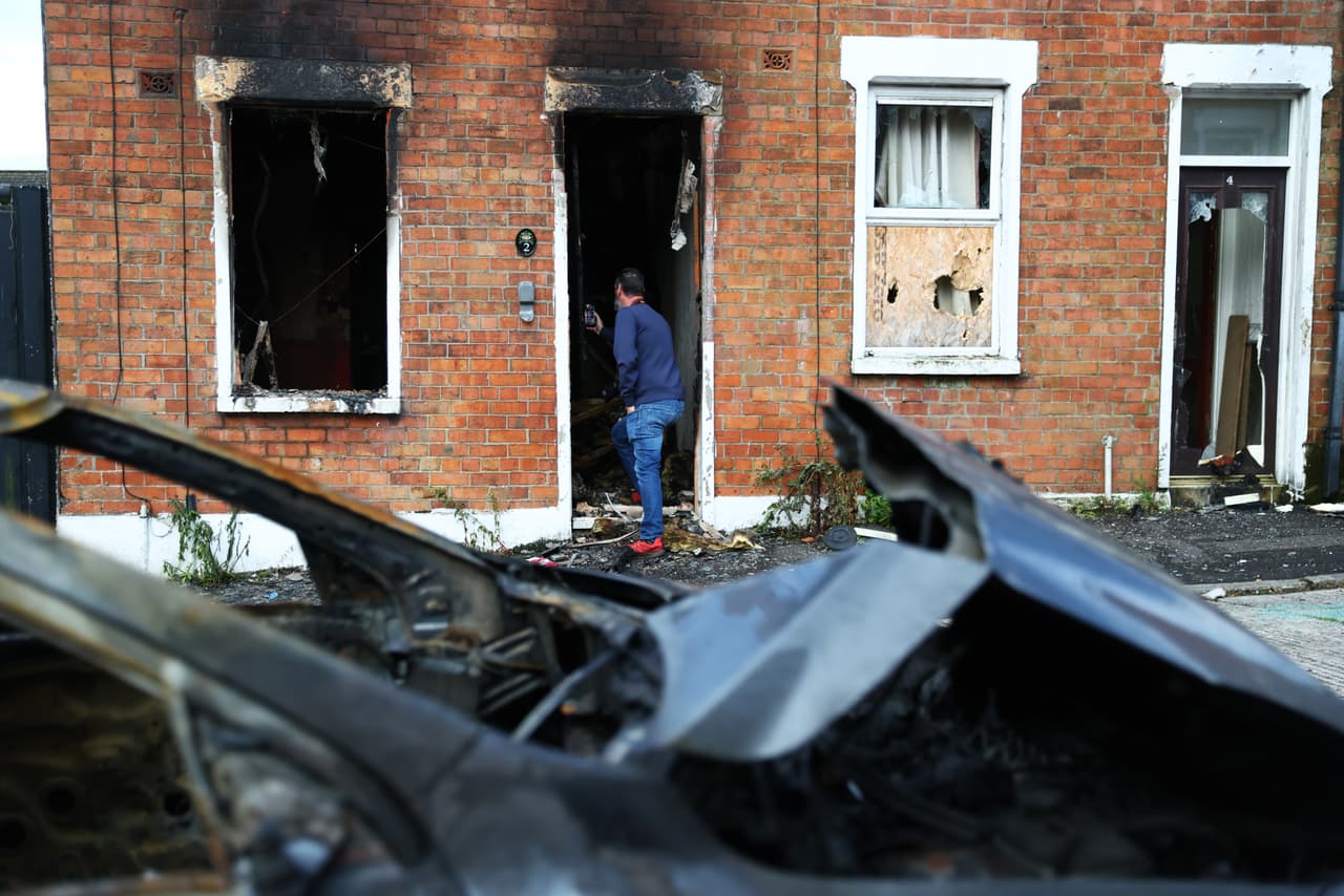 Un hombre fotografía los daños en una vivienda tras el estallido de disturbios a última hora del martes en el este de Belfast. (Foto AP/Peter Morrison)