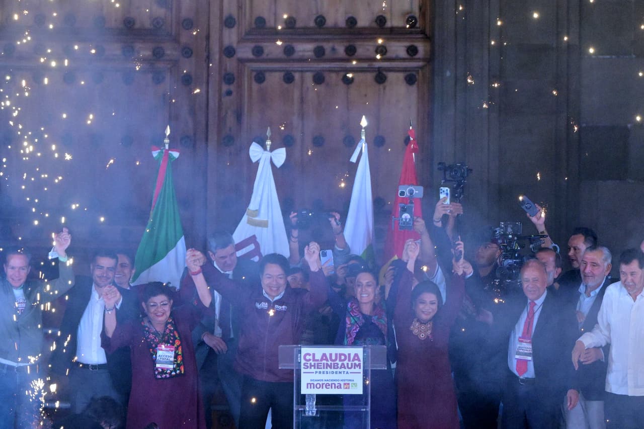 Claudia Sheinbaum, al centro de la foto, levanta las manos junto con líderes de su partido político, Morena.