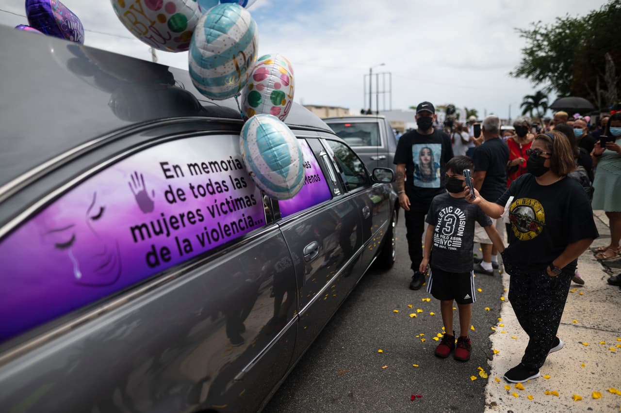 Una mujer toma una foto de un vehículo cuyas ventanas están blasonadas con un mensaje que dice en español: "En memoria de todas las mujeres víctimas de violencia", durante la procesión fúnebre de Keishla Rodríguez.