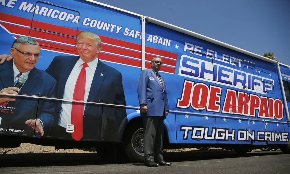 El exsheriff del condado de Maricopa, Joe Arpaio, posa junto a un automóvil de su campaña tapizado con una foto donde se le puede ver junto a Donald Trump.