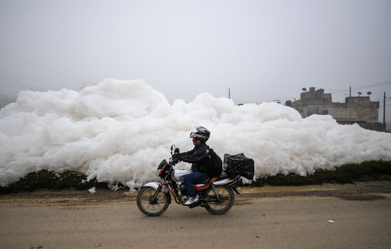 Un motociclista pasa por la espuma que invadió el barrio Los Puentes, en Mosquera. 
<br>
<br>"Esto es producto de la contaminación, de la mala disposición de los residuos, materiales, animales muertos, basura, grasas y detergentes", explica a la AFP Sergio Valero, director de gestión del riesgo de Mosquera, municipio de la cuenca baja del rio Bogotá. 
<br>