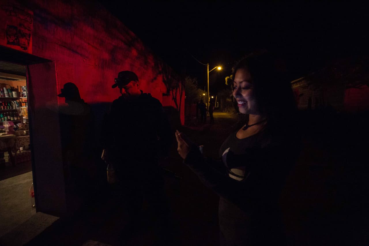 Sarai, 18, oriunda de La Joya, como Rubí, se entusiasma al comprobar que su teléfono inteligente agarra señal de internet fuera de la tiendita de abarrotes donde trabaja. Debido al evento de los XV de Rubí una empresa ofrece internet de pago durante unas horas. La casa de Sarai tiene letrina en vez de baño, y el pueblo, de aproximadamente 200 habitantes, carece de cobertura de teléfono e internet. Almudena Toral