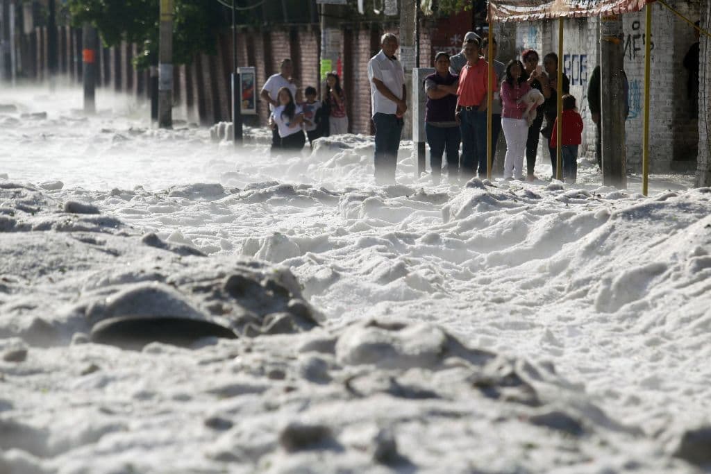 La gente mira de las aceras la acumulación de granizo en las calles.