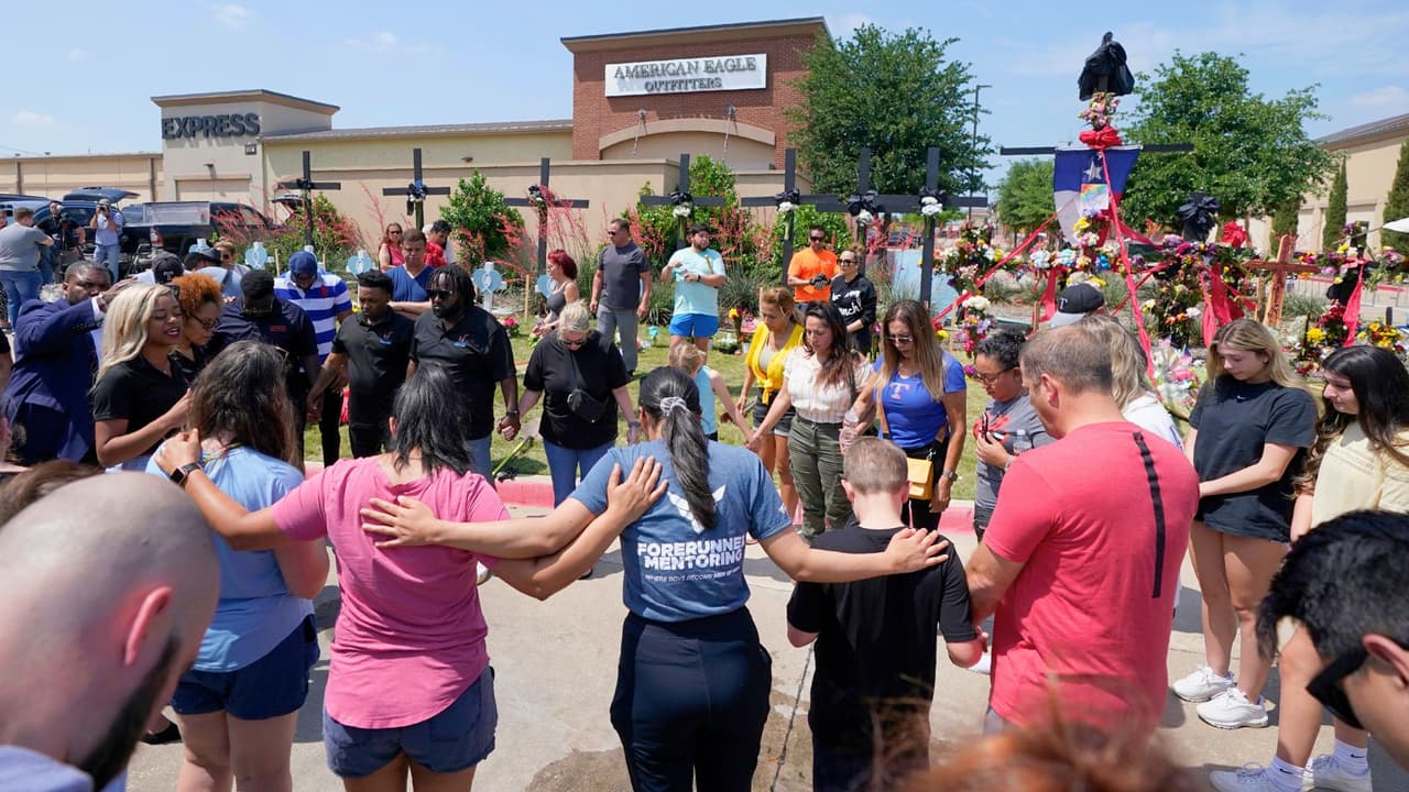 Un grupo de personas oran frente a un monumento improvisado junto al centro comercial donde varias personas fueron asesinadas, el lunes 8 de mayo de 2023, en Allen, Texas.