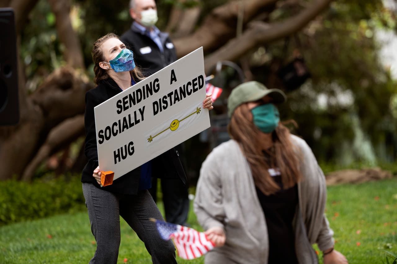 <b>“Te envío un abrazo con distancia social”</b>. Un grupo de jóvenes saludan desde la calle a los residentes de un hogar para jubilados en San Diego, California. Desde que los ancianos se encuentran encerrados en cuarentena cada tarde los trabajadores de la institución se acercan al edificio para bailar, mostrar carteles, ondear banderas y gritar mensajes de ánimo. 8 de abril.