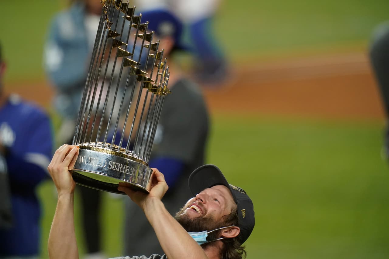 El lanzador de los Dodgers de Los Ángeles Clayton Kershaw celebra con el trofeo después de derrotar a los Rays de Tampa Bay en Arlington, Texas.