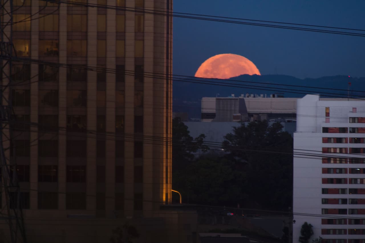 La luna se oculta esta mañana del 14 de noviembre detrás de los edificios del Barrio Chino de Los Ángeles.