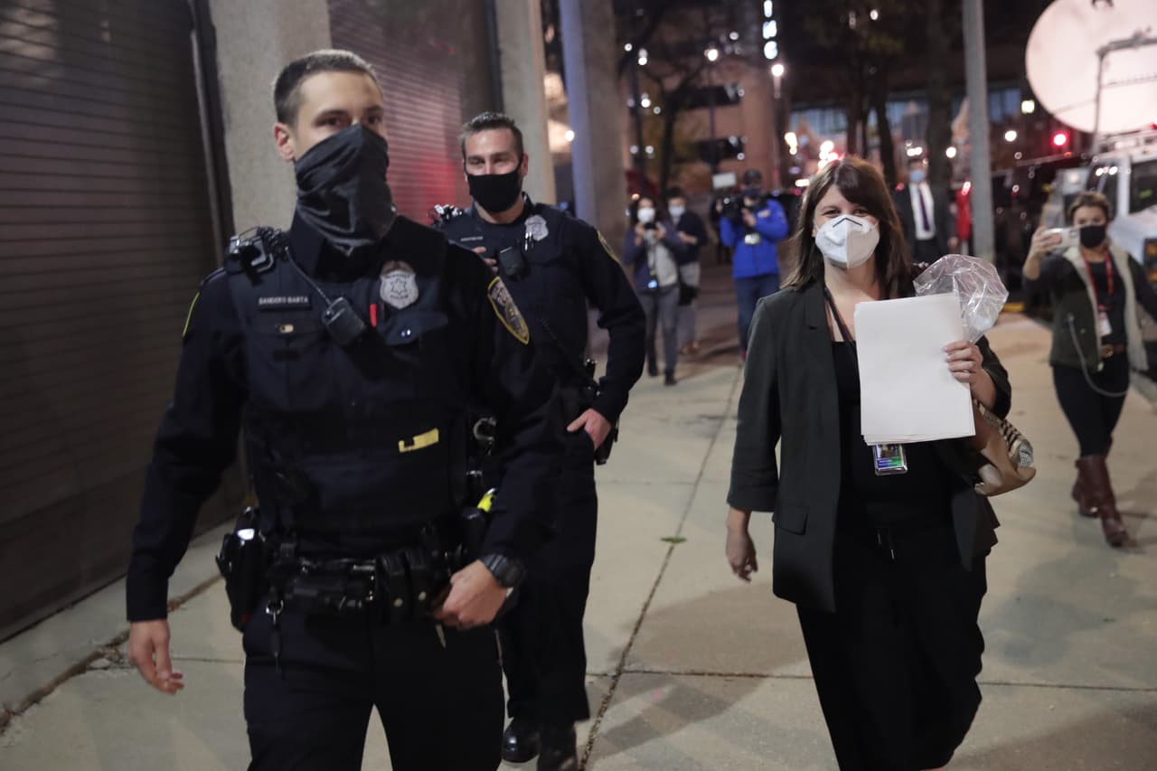 Claire Woodall-Vogg, directora ejecutiva de la comisión electoral de Milwaukee, es escoltada por la policía desde la ubicación del conteo central donde se contaban las boletas de voto en ausencia con el conteo final el 4 de noviembre de 2020.