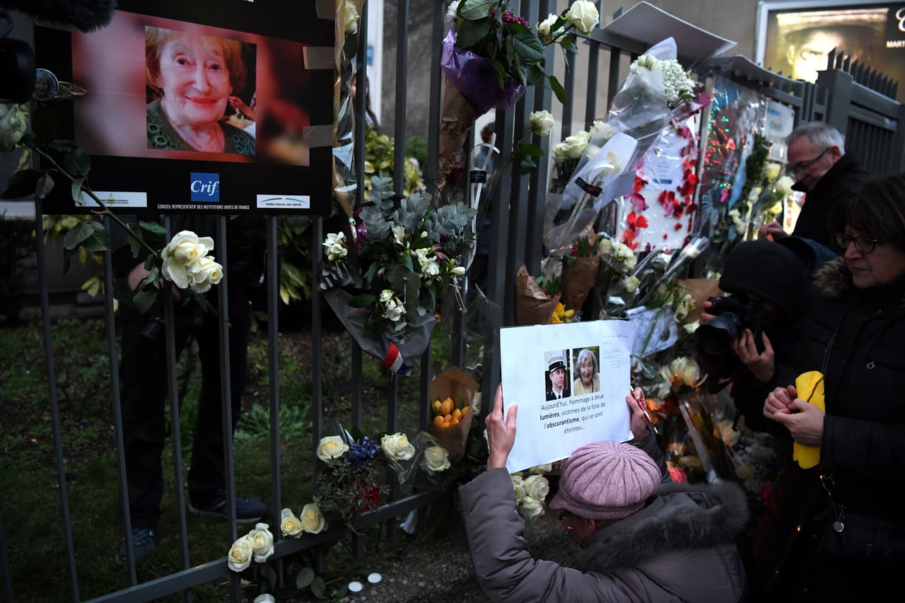 A woman holds a photograph of slain Lieutenant-Colonel Arnaud Beltrame and Mireille Knoll as she gathers with others at the entrance to an apartment building in Paris on March 28, 2018, at the conclusion of a march in memory of Mireille Knoll, the 85-year-old Jewish woman murdered in her home in what police believe was an anti-Semitic attack. The partly burned body of Mireille Knoll, who escaped the mass deportation of Jews from Paris during World War II, was found in her small apartment in the east of the city on March 23, by firefighters called to extinguish a blaze. / AFP PHOTO / ALAIN JOCARD (Photo credit should read ALAIN JOCARD/AFP/Getty Images)