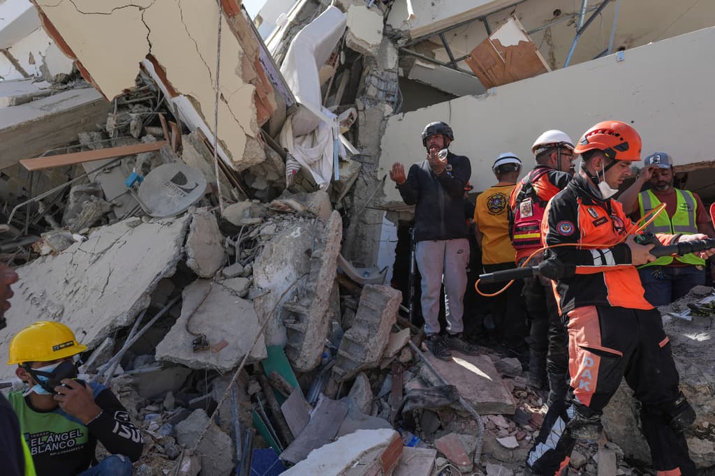 El voluntario Jean Sosa, quien se unió a los equipos de rescate que buscaban supervivientes del terremoto, explica lo que vio tras adentrarse bajo los escombros de un edificio donde los rescatistas intentan llegar a personas atrapadas en La Guaira, Venezuela, el lunes 29 de junio de 2026. (Foto AP/Matias Delacroix)