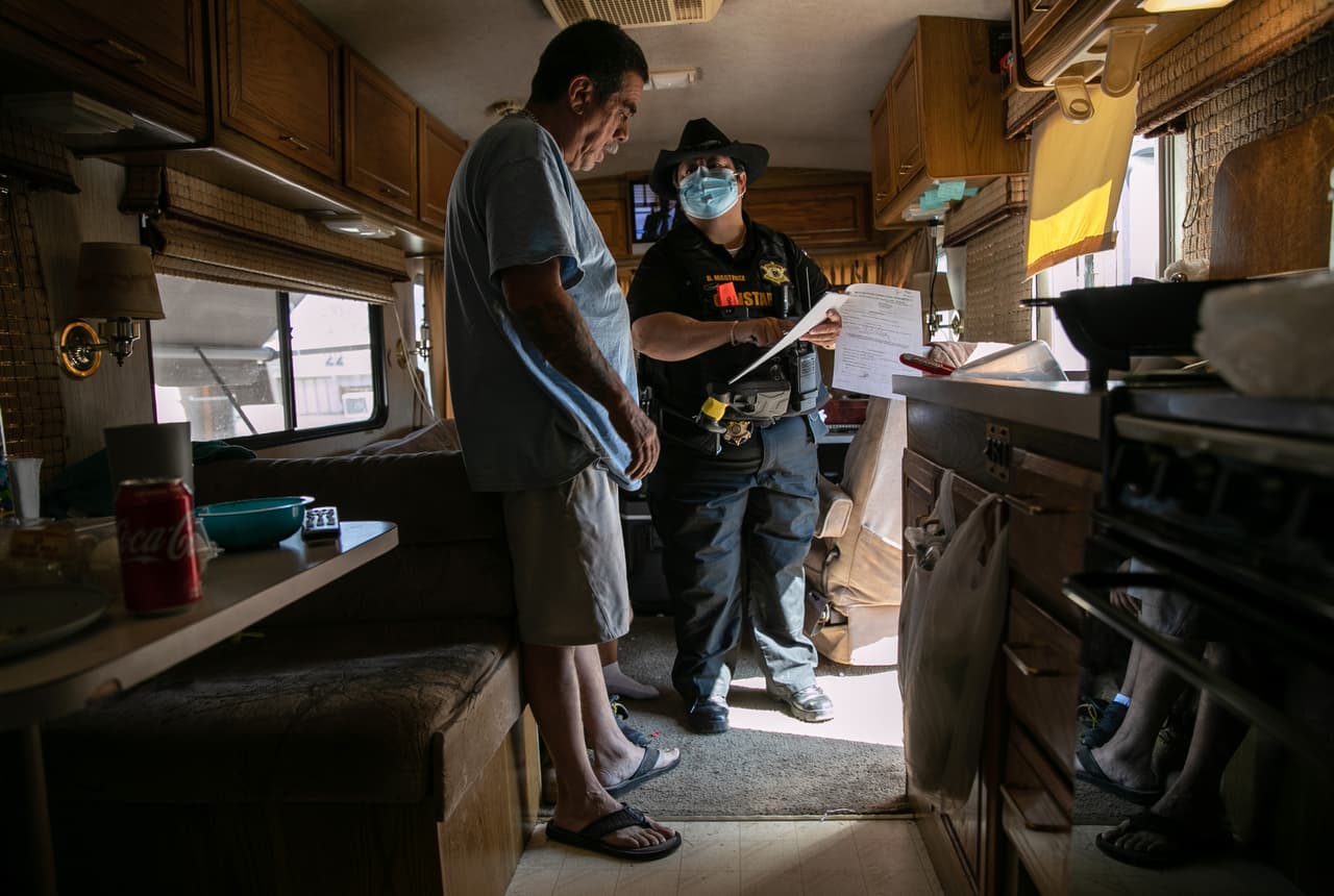 Un agente del condado de Maricopa, en Arizona, muestra a un ciudadano los documentos de corte que ordenan el desalojo de esta familia en octubre de 2020.