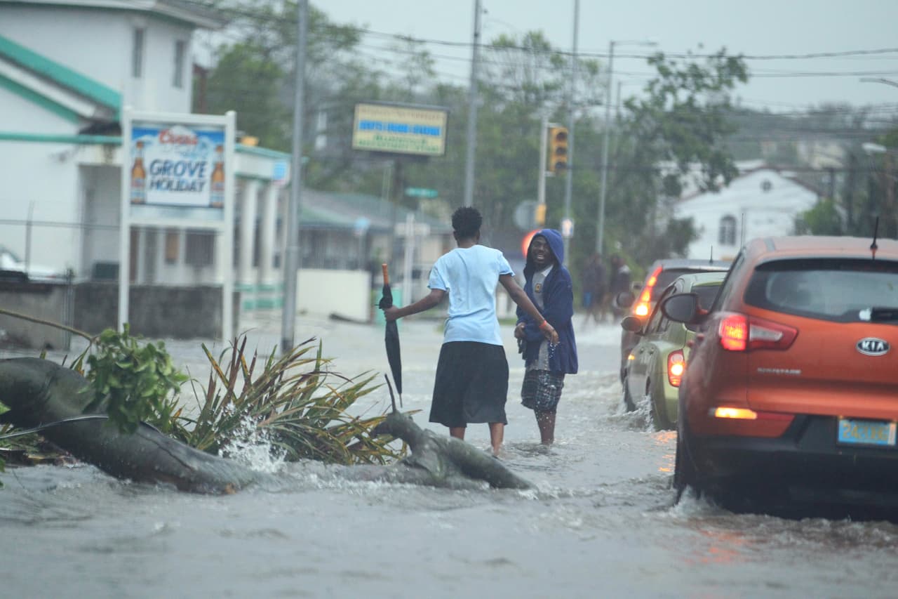 Residentes y automóviles evitan chocar contra los árboles caídos durante la tormenta, en Nassau, Bahamas.