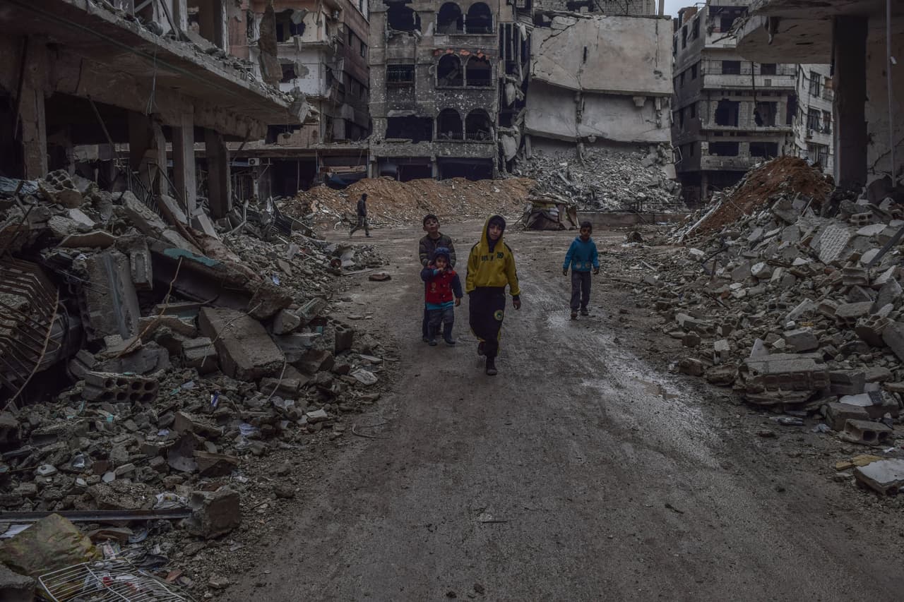 17 de febrero. Niños caminan entre los escombros de los edificios tras un ataque aéreo en la ciudad de Harasta.
