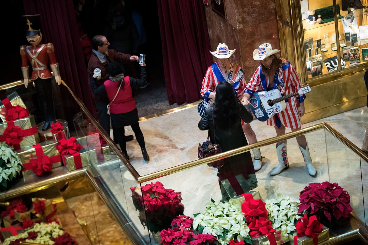 Unos músicos vestidos como vaqueros con banderas hablan con las personas dentro del lobby de la torre.
<br>