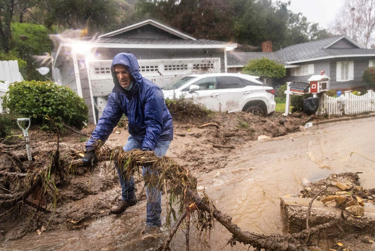Jeffrey Raines limpia una calle que recibió ramas y lodo durante la tormenta de este lunes en Los Ángeles.