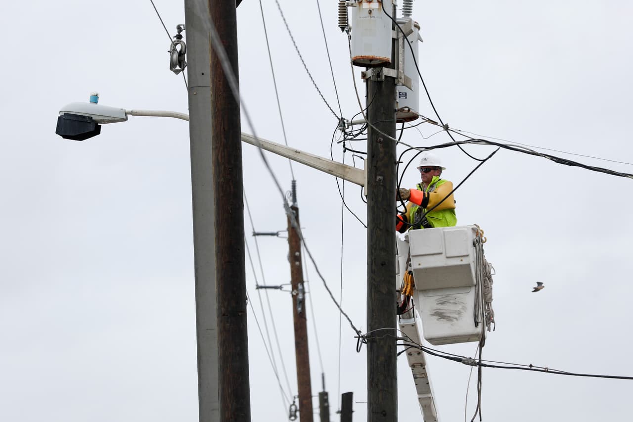 Un hombre trabaja en restablecer el servicio eléctrico en la costa de Ormond, Florida.