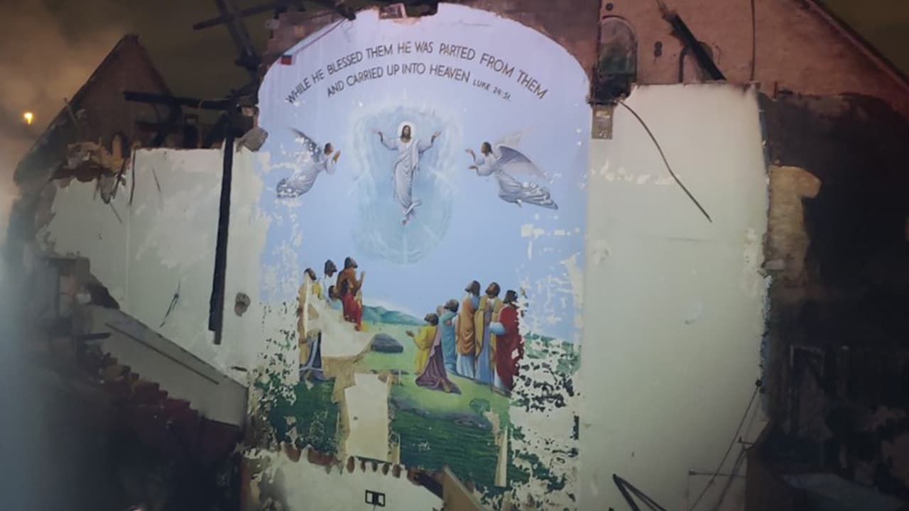 El mural muestra a 
<b>Cristo ascendiendo al cielo</b>, flanqueado por dos arcángeles y un versículo de la Biblia. 
<br>