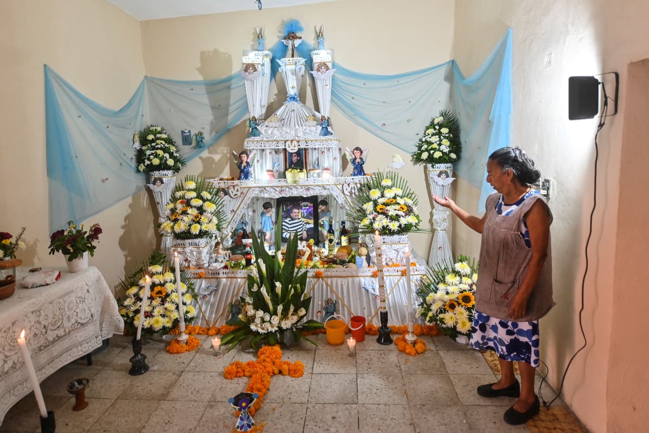 Una mujer se encuentra junto a un Altar Monumental dedicado a su pariente Francisco Cruz de 53 años, quien murió víctima de COVID-19 en la ciudad de Nueva York, en Huaquechula, estado de Puebla, México, el 1 de noviembre de 2020.