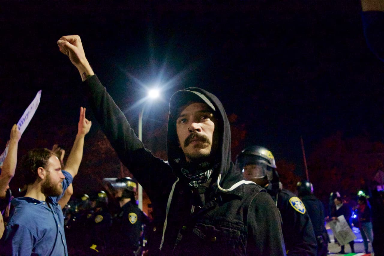 Este joven de #OcuppyOakland protesta frente al grupo de policías que intenta frenar la marcha contra Donald Trump. La manifestación fue declarada como "asamblea ilegal" por las autoridades.