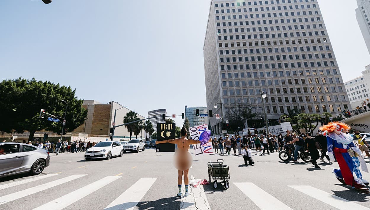 A poca distancia del enfrentamiento entre autoridades y manifestantes, otras personas, una sin ropa y otros disfrazados, exigían un alto a los operativos de ICE en Los Ángeles, que desde el viernes 6 de junio han impactado a decenas de familias.