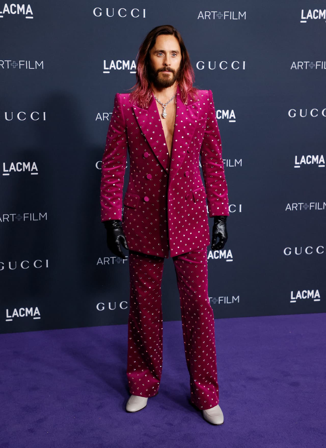 Jared Leto lució un traje de terciopelo fucsia de Alessandro Michele que hacía juego con su color de cabello. Las lentejuelas en el pantalón y chaqueta le daban un extra a su atuendo. El actor combinó su look con mocasines color crema y guantes de cuero negros.