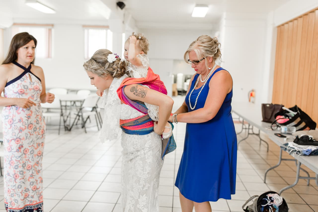 Las damas de honor ayudaron a Mort a envolver a la pequeña en un fular, un seguro y confortable portabebés armado con una larga tela sobre la espalda. Fue escogido para que no desentonara con los colores crema de los vestidos de madre e hija.