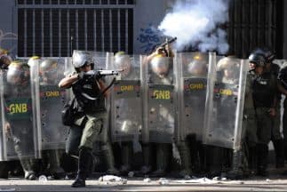 Policías antomotines durante una manifestación en las calles de Caracas. Un agente abre fuego con un rifle a una multitud contraria al gobierno de Nicolás Maduro.