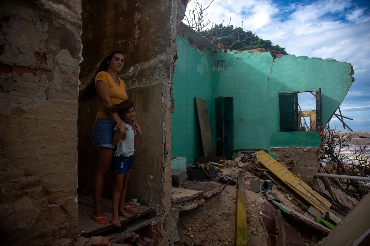 El que fue un balneario apacible al norte de 
<a href="https://www.univision.com/temas/brasil">Rio de Janeiro (Brasil)</a>, hoy es un escenario apocalíptico, con casas arrasadas por la erosión del implacable avance del mar. Una crisis que se ve agudizada por el calentamiento global.
<br>
<br>En la foto, Raissa Boamorte y su hija en lo que fue su casa de playa de Atafona, en Sao Joao da Barra. 
<br>
