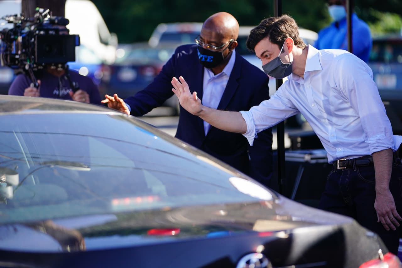 Los candidatos demócratas al Senado de los Estados Unidos, Jon Ossoff y el reverendo Raphael Warnock durante un evento para entregar letreros en el césped en un evento de campaña el 3 de octubre de 2020 en Lithonia, Georgia. Los dos esperan derrocar a los senadores titulares David Perdue y Kelly Loeffler.