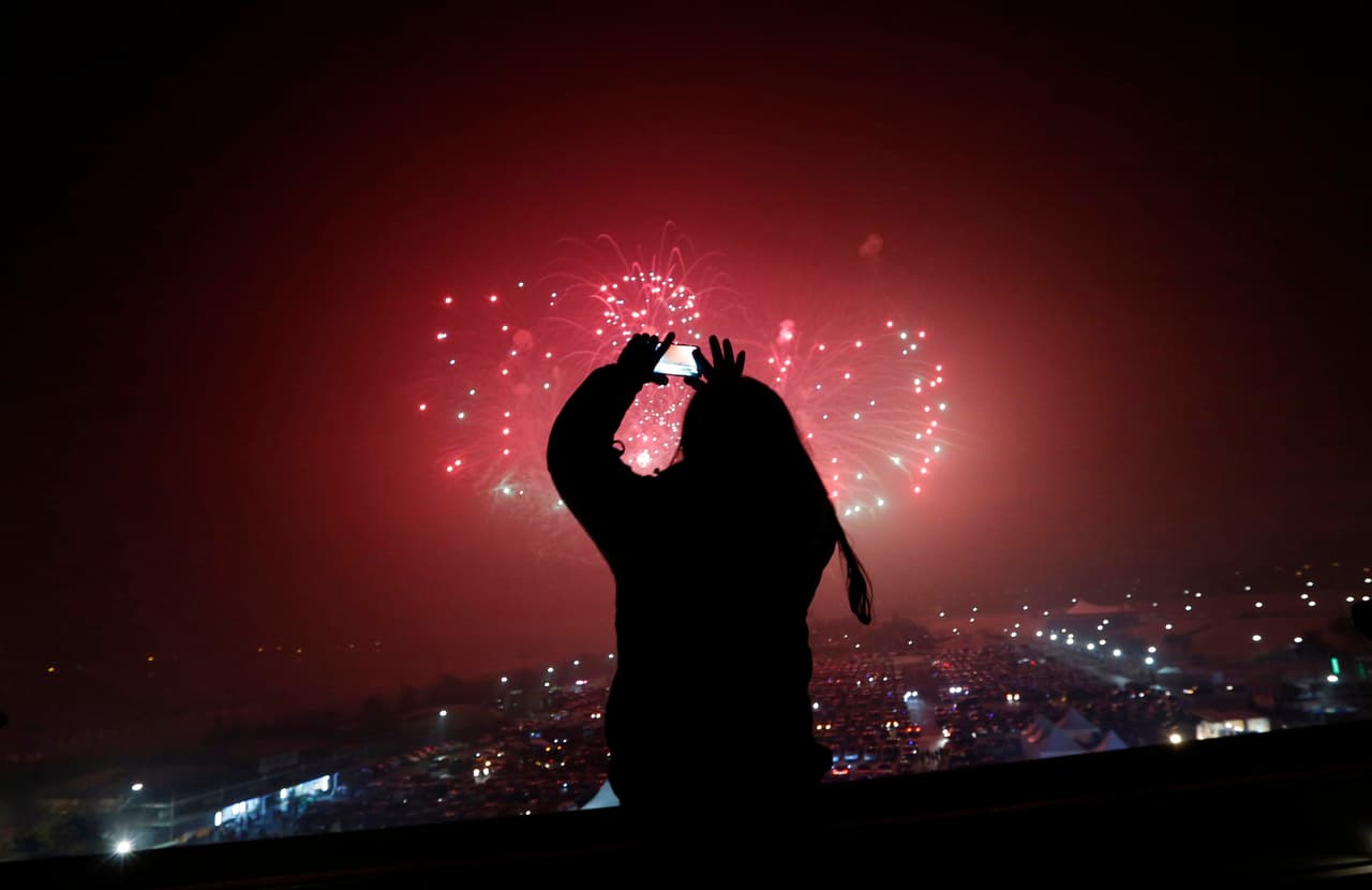 Una mujer capta con su teléfono móvil los fuegos artificiales por la celebración del Año Nuevo en el Pabellón Imjingak, en Corea del Sur.