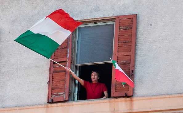 Un residente agita una bandera italiana en el distrito de Garbatella de Roma durante un 
<i>flashmob</i> (palabra en inglés que define una reunión pública en la que las personas realizan un acto y luego se dispersan, generalmente organizado a través de Internet o las redes sociales) 
<b>en el 'Día de la Liberación'. </b>