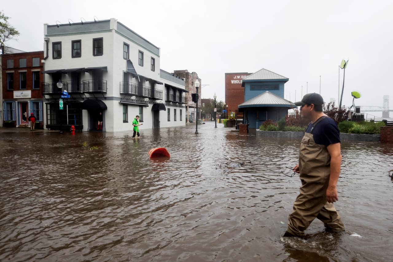 Varios vecinos caminan exploran una calle inundada en Wilmington, Carolina del Norte.