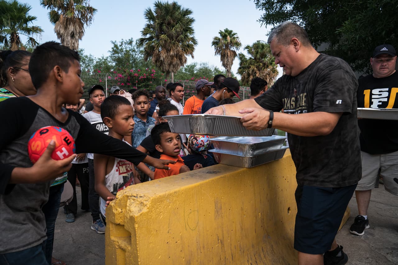 La organización de Michael Benavides (cargando las bandejas, en la imagen) distribuye desayuno y cena todos los días a los solicitantes de asilo.