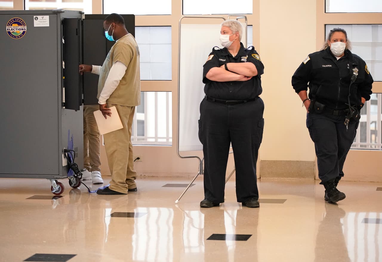 Uno de los guardas mira a uno de los detenido de la cárcel del condado de Cook que utiliza una pantalla táctil para emitir su voto.