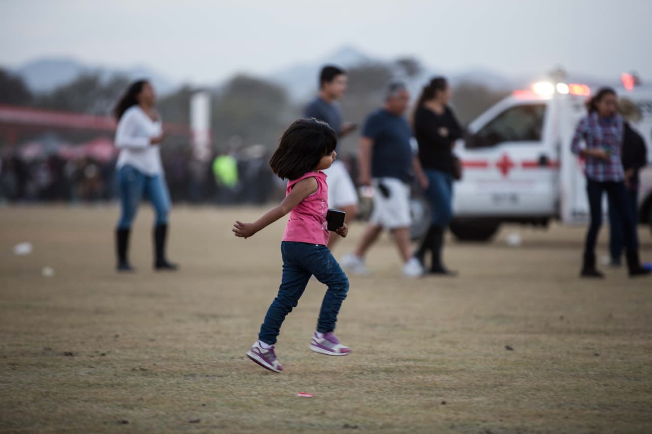 Una niña corre por la explanada del concierto con un celular inteligente en la mano. Dos de cada tres personas en México posee un teléfono inteligente, en un país donde el 46.2% vive en la pobreza.
<i>Almudena Toral</i>