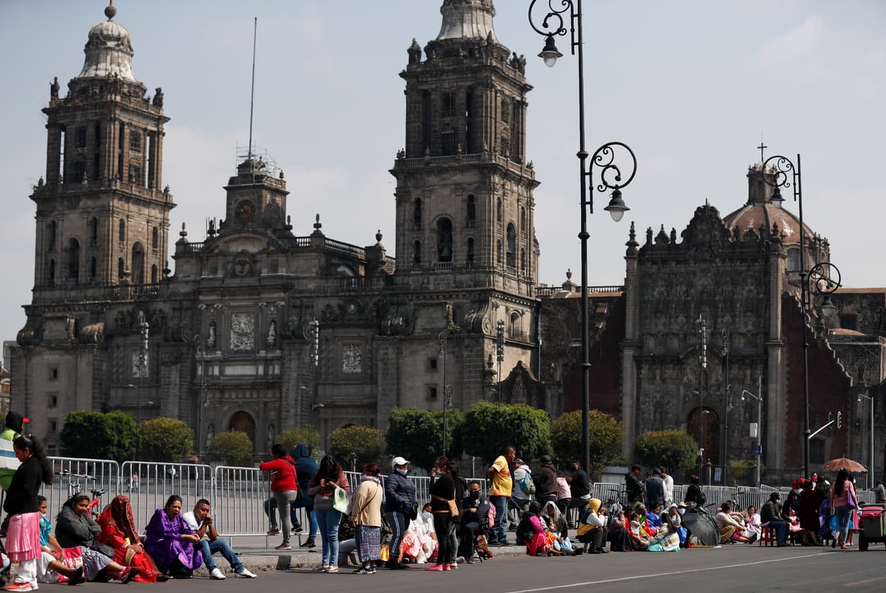 Los miembros de las comunidades indígenas, algunos con máscaras, se sientan frente a la plaza cerrada de Zócalo con la Catedral Metropolitana el lunes 11 de mayo de 2020. (Archivo)