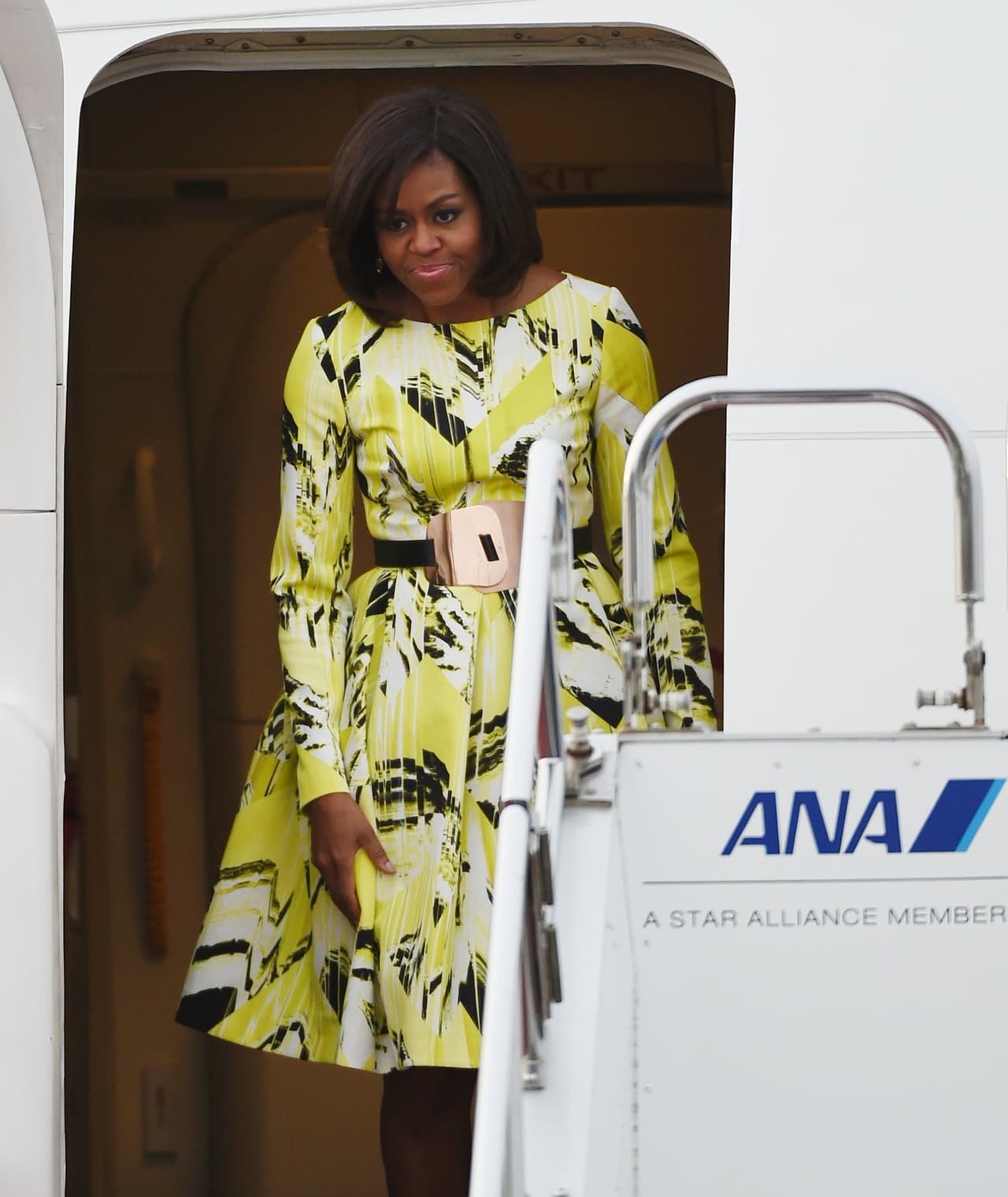 Lo que hizo que las mujeres estadounidense se enamoraran locamente del estilo de Michelle Obama fue justamente que ella marcó el retorno de los vestidos femeninos, esos de cintura afinada y una falda de amplio vuelo, una silueta que a la mayoría le viene bien. Esa cierta democracia estilística se hizo visible una vez más con este vestido de estampado amarillo de Kenzo y cinturón de Roksanda.