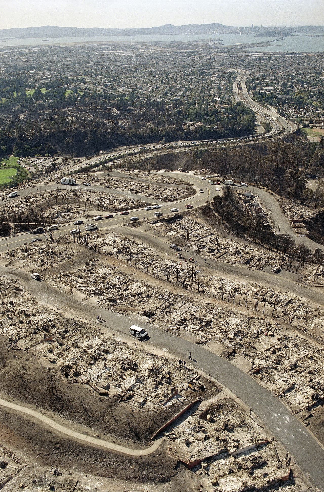 Vista aérea de los restos quemados de viviendas en la sección de Hiller Heights de las colinas de Oakland, California, el miércoles 23 de octubre de 1991.
<br>
<br>Al fondo se observan la autopista 24, el puente de laBbahía y el horizonte de San Francisco. 
<br>
<br>Al menos 25 personas murieron en el incendio más caro de Estados Unidos.