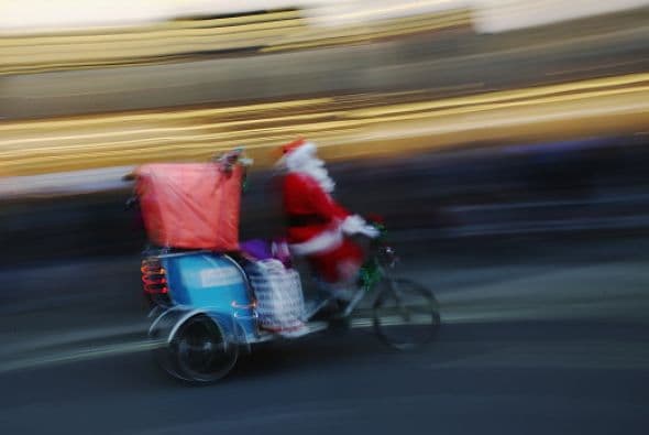 Un hombre vestido como Santa lleva a los paseantes a lo largo de Regent en triciclo en Londres.