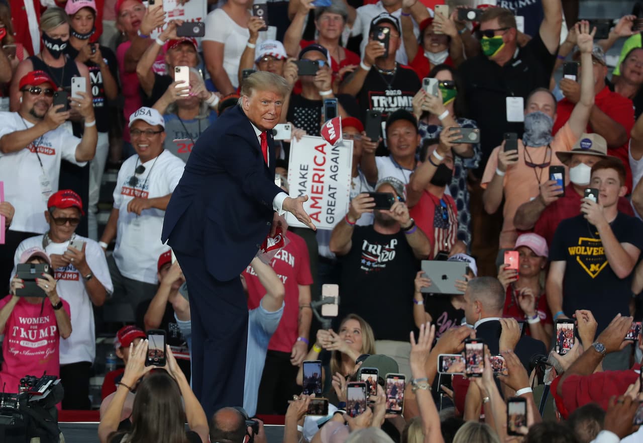 El presidente Donald Trump lanza una mascarilla con las siglas MAGA a la multitud cuando llega al escenario para su evento de campaña en el Aeropuerto Internacional Orlando Sanford el 12 de octubre de 2020 en Sanford, Florida.