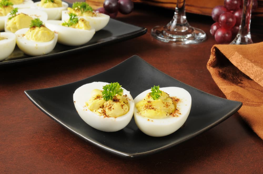 Huevo y picante. Si la primera opción no te convenció del todo, puedes probar esta variedad. Se trata de los mismos pasos para conseguir la forma de los huevos solo vas a cambiar el relleno. Cuando tengas las yemas echas puré, agrega rábano picante, mayonesa, mostaza picantes, pimienta de cayena y cebollines y listo. Para decorar también puedes usar los cebollines.