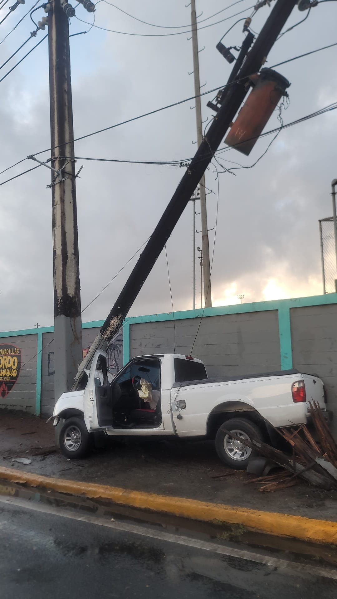 Mazda 2000 blanca impacta poste de luz.