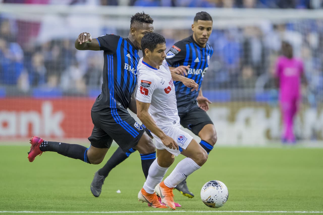 Carlos Pineda logra salir entre dos jugadores del Montreal Impact.