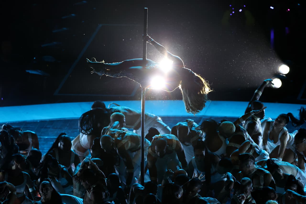 JLo usó el escenario del estadio Hard Rock de Miami para dar 
<b><a href="https://www.univision.com/famosos/jlo-muestra-como-sufrieron-sus-piernas-aprendiendo-pole-dancing-para-hustlers-nunca-me-habia-lastimado-asi-video">una demostración de 'pole dance', tal como la vimos en 'Hustlers</a></b>' . Antes, la actriz y cantante dejó el mono negro para cambiarlo por un body plateado. El nuevo modelo, también Versace, se fabricó con 800 piezas de cuero plateado, 12 mil piezas de lentejuelas plateadas y 15 mil cristales de Swarovski. Se cosió a mano durante 700 horas sobre un tul de tono piel, explicaron los estilistas.