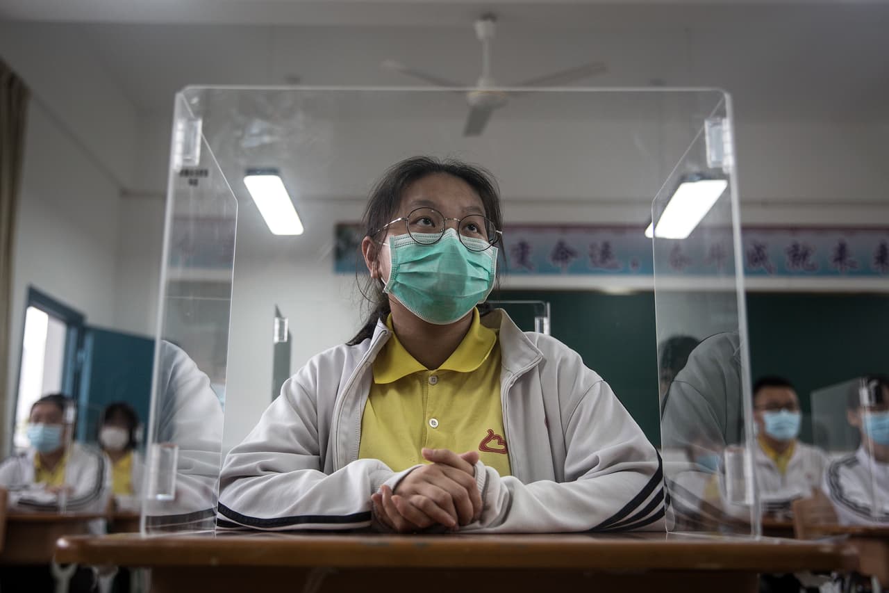 Estudiantes separados por cubículos transparentes atienden una clase en una escuela secundaria de Wuhan, China. En esta ciudad se originó la pandemia a finales de 2019. 6 de mayo.