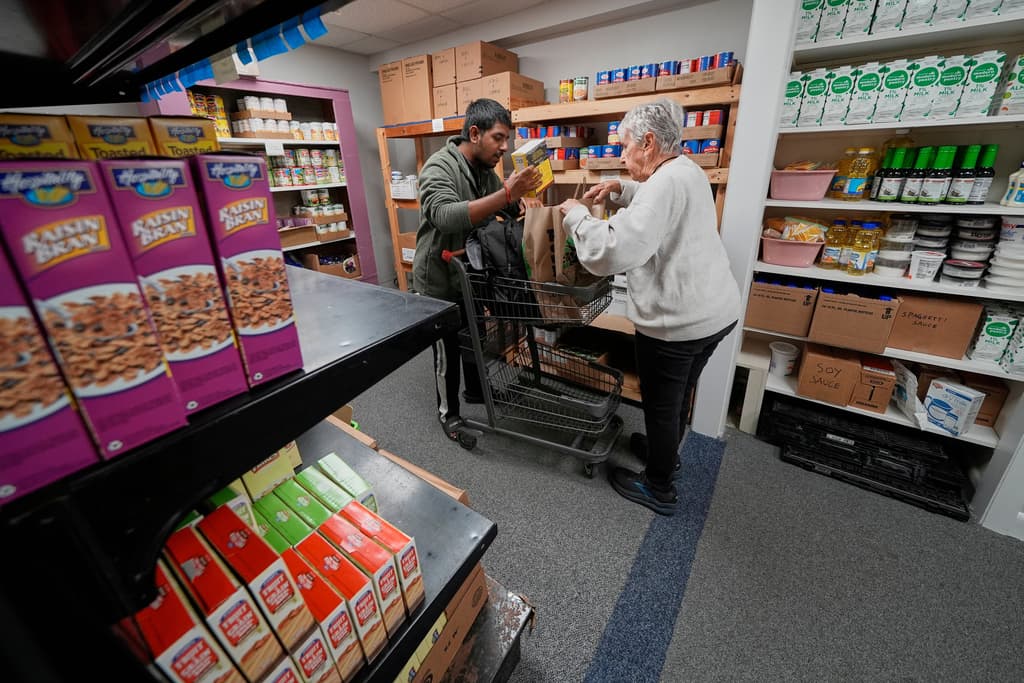 La voluntaria Betty McNeely, derecha, ayuda a un hombre a empacar alimentos en Project Feed, una despensa de alimentos de emergencia en Portland, Maine, el 28 de octubre de 2025.